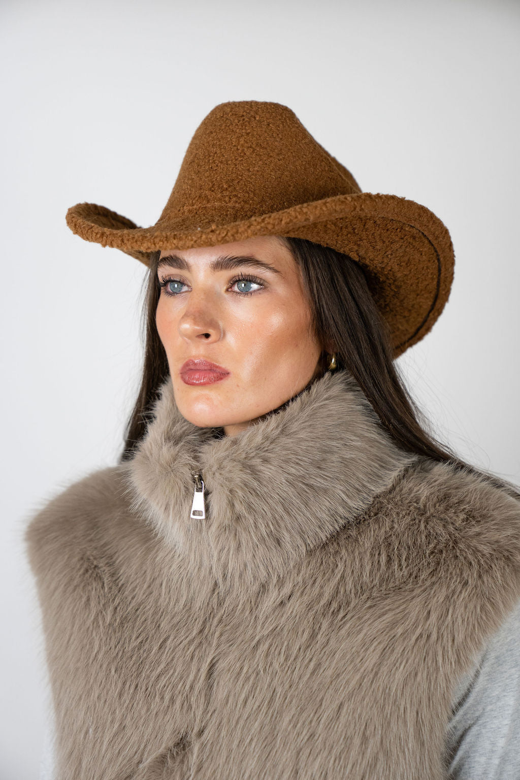 Model wearing the Cowboy Hat in Mocha by Angel Wings by Lucy, styled with a faux fur vest for elevated western-inspired winter dressing.