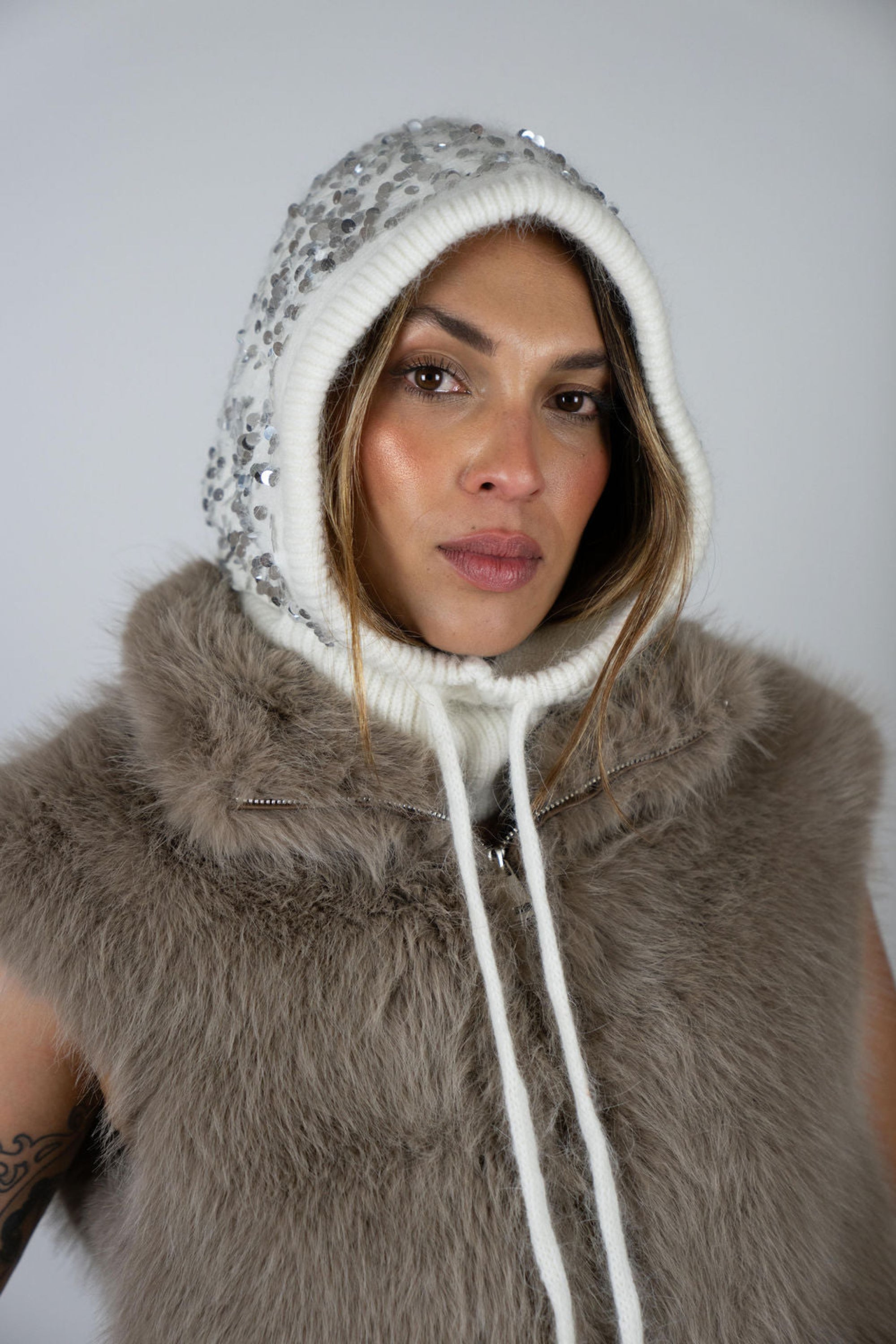 Model wearing the Sequin Knit Hood in Snow by Angel Wings by Lucy, a luxury knit hood with subtle sequin detailing designed for elevated winter and resort styling.