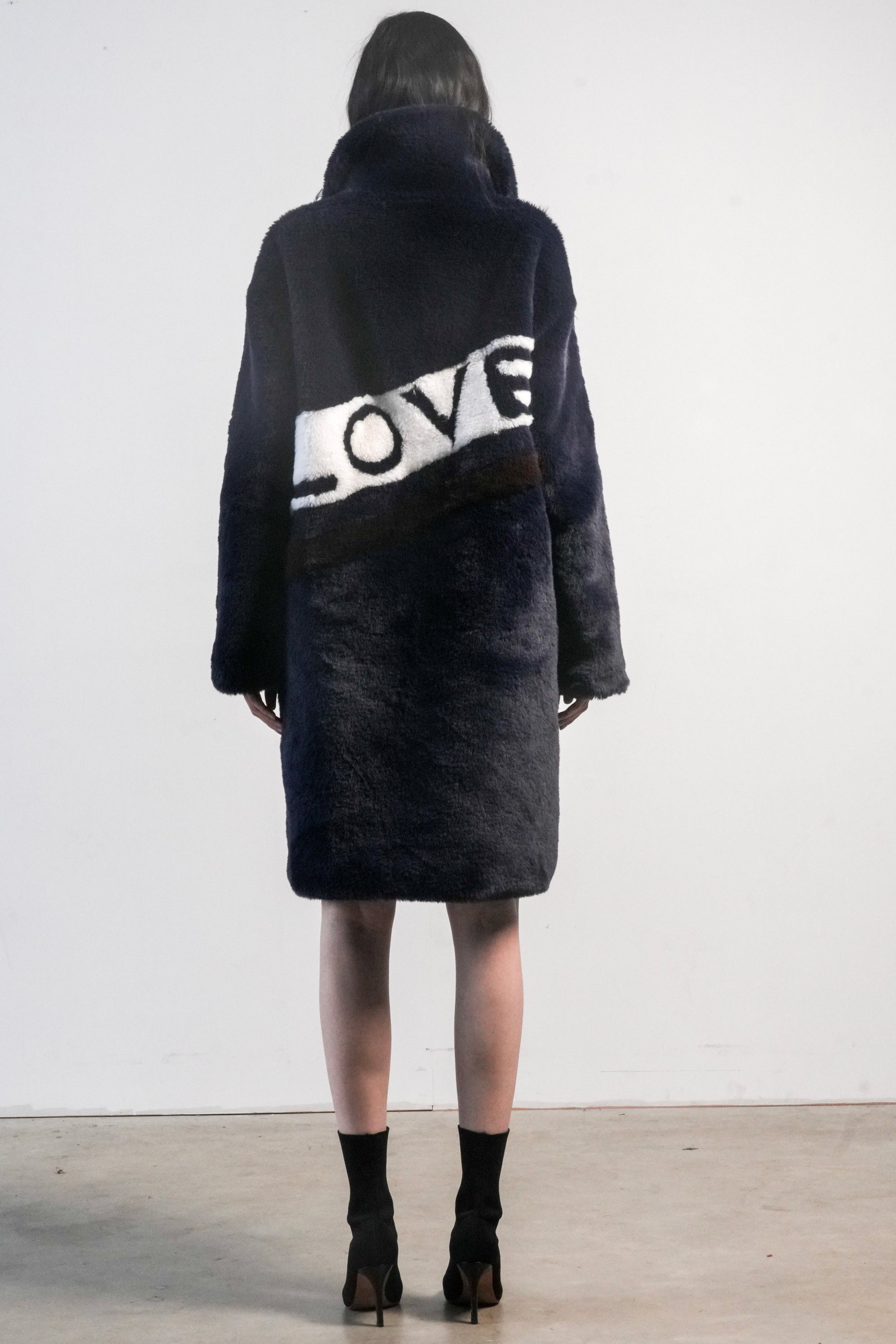 Back view of navy faux fur jacket with white diagonal stripe and bold black “LOVE” lettering — from the Mr. Greys collection.
