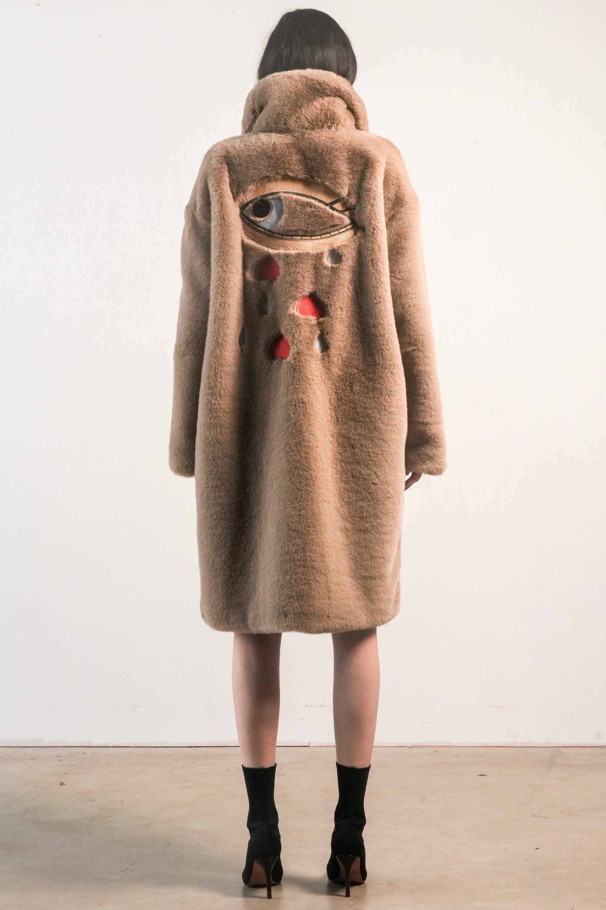Back view of camel-colored faux fur jacket with large embroidered evil eye and red-grey teardrop details — from the Mr. Greys collection.