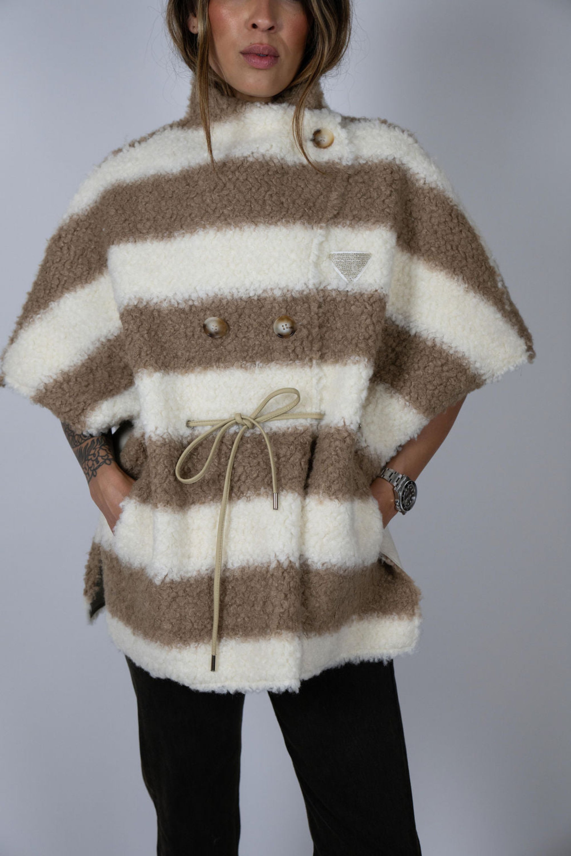 Angel Wings by Lucy wool cape in beige and ivory stripe, oversized with short sleeves, drawstring waist, and buttons, shown on model up close