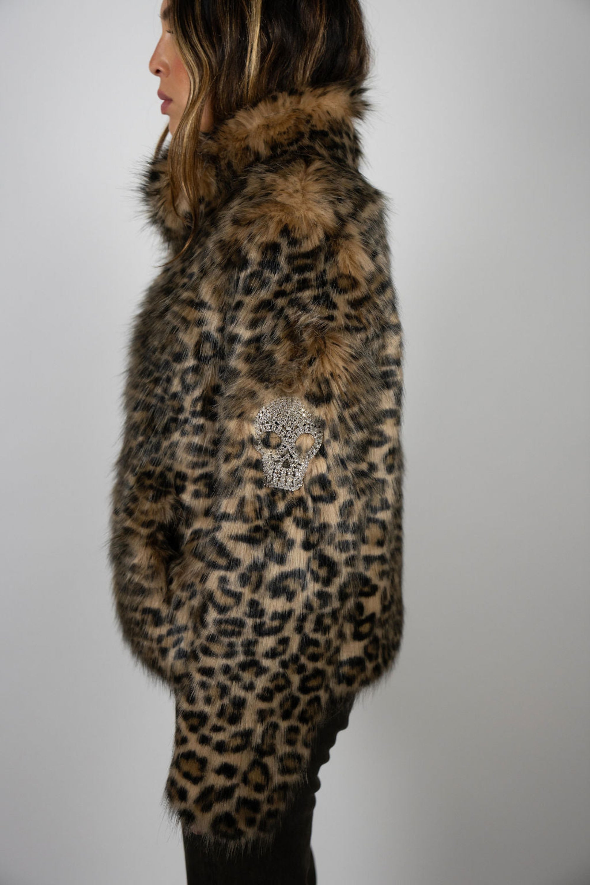 Angel Wings by Lucy cropped leopard faux fur jacket with skull detail on sleeve, high collar, and side pockets, worn by model from side angel.