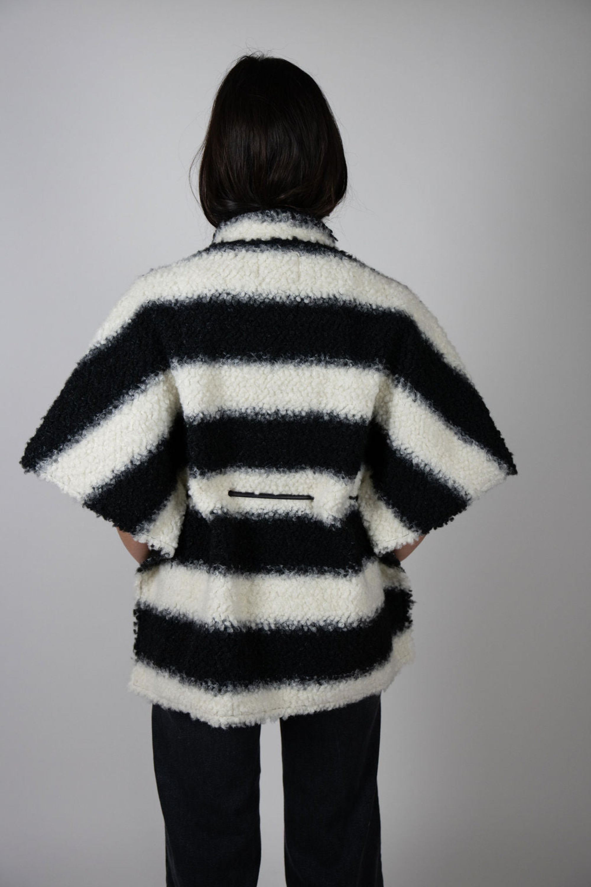 Angel Wings by Lucy black and white striped wool cape, oversized with short sleeves, buttons and drawstring waist, shown on model from back.