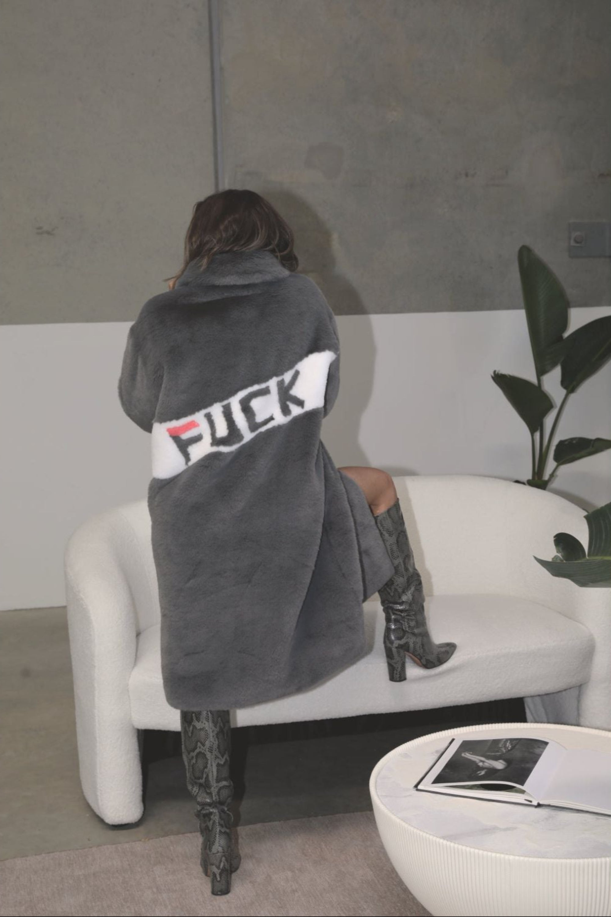 Back view of slate grey faux fur jacket with bold white diagonal panel featuring “FUCK” slogan in graphic lettering — part of the Mr. Greys collection.