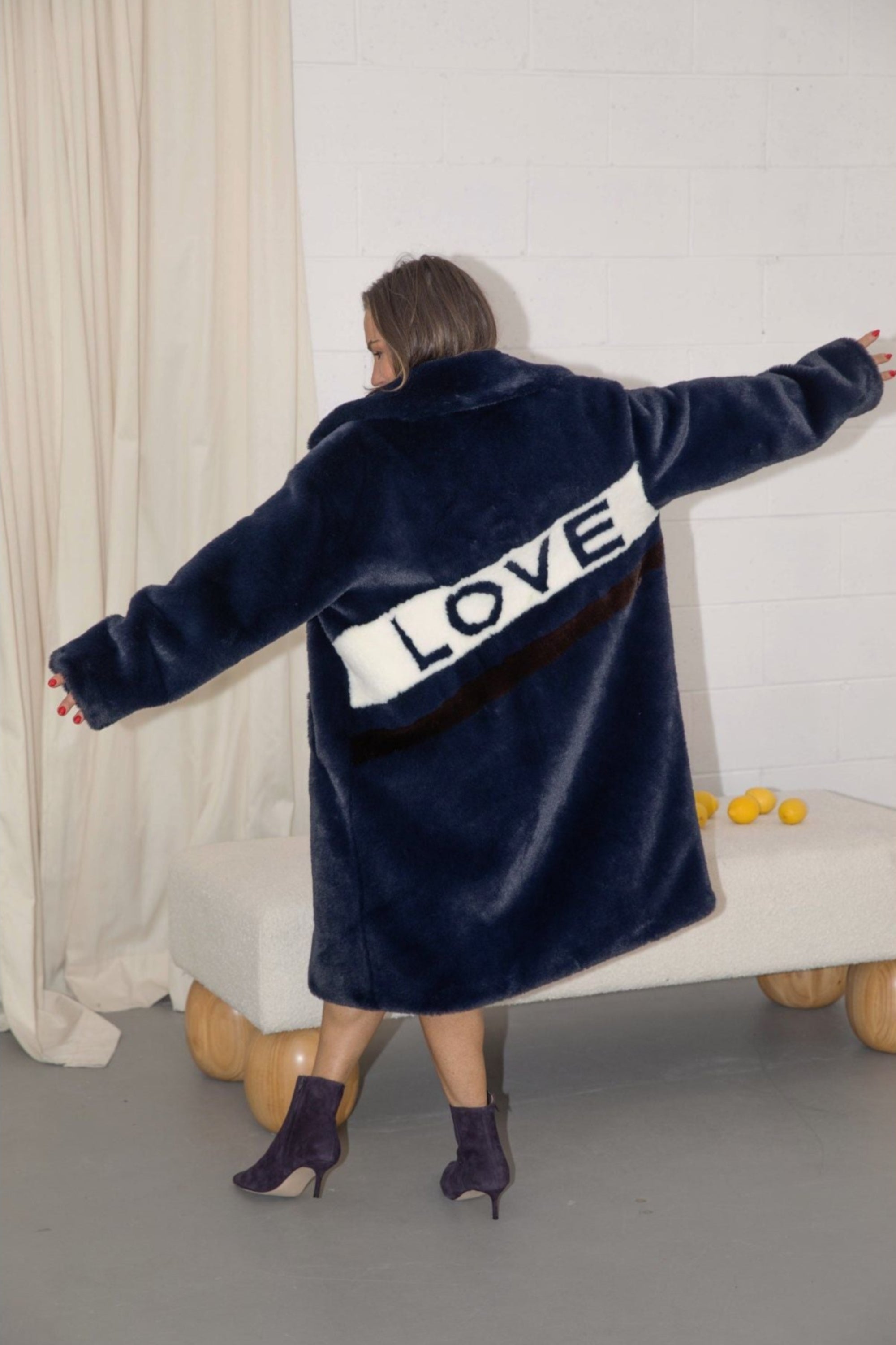 Back view of navy faux fur jacket with white diagonal stripe and bold black “LOVE” lettering — from the Mr. Greys collection.