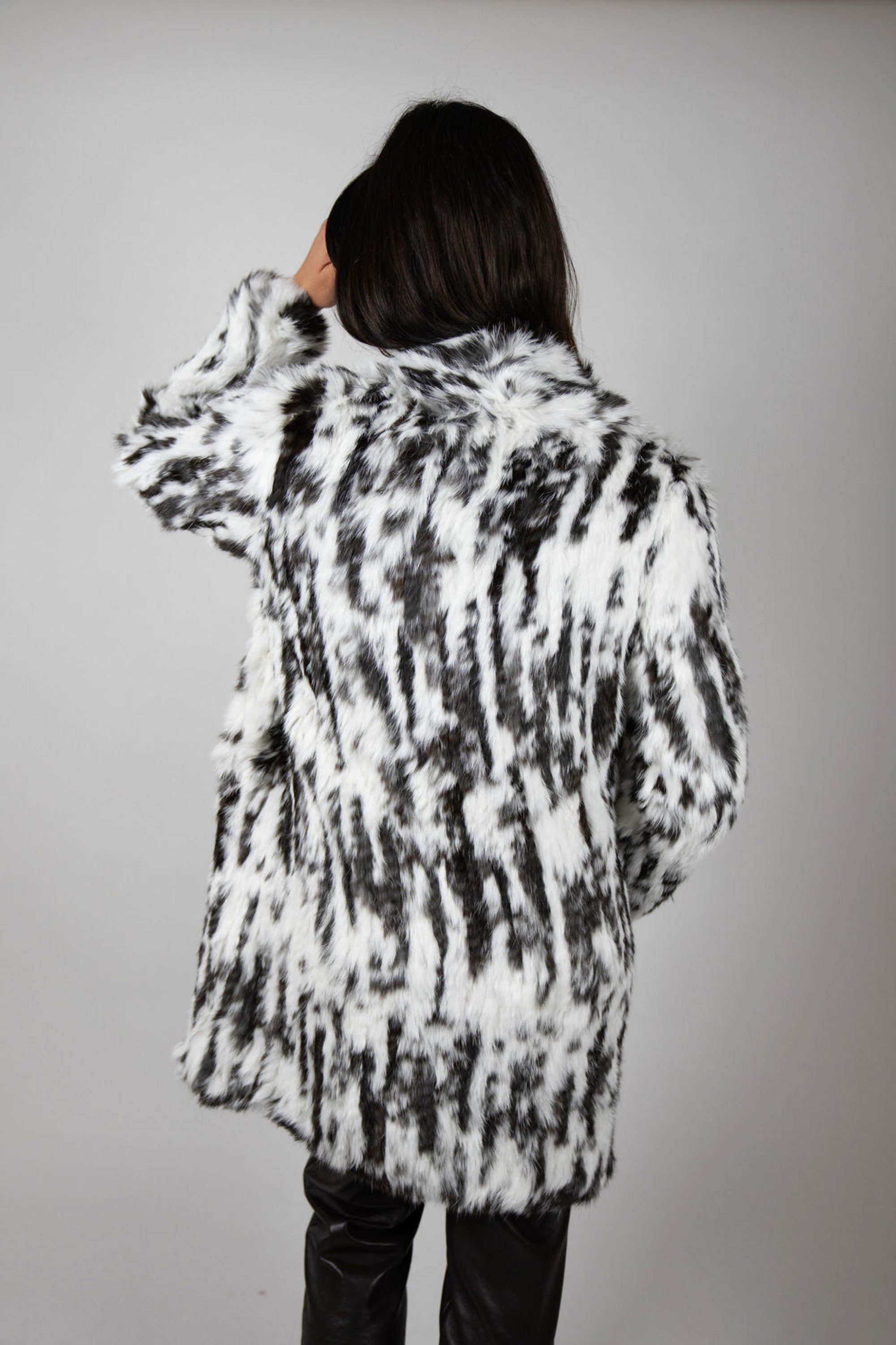 A clean back shot reveals the symmetrical print placement and gentle cocoon silhouette that gives the coat its signature movement.