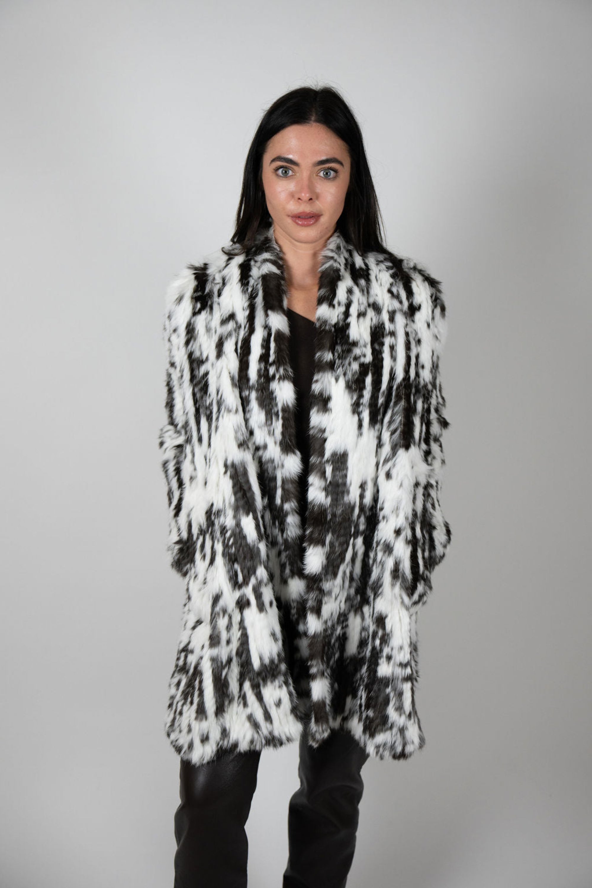 Model standing straight in snow leopard faux fur swing coat with a neutral expression.