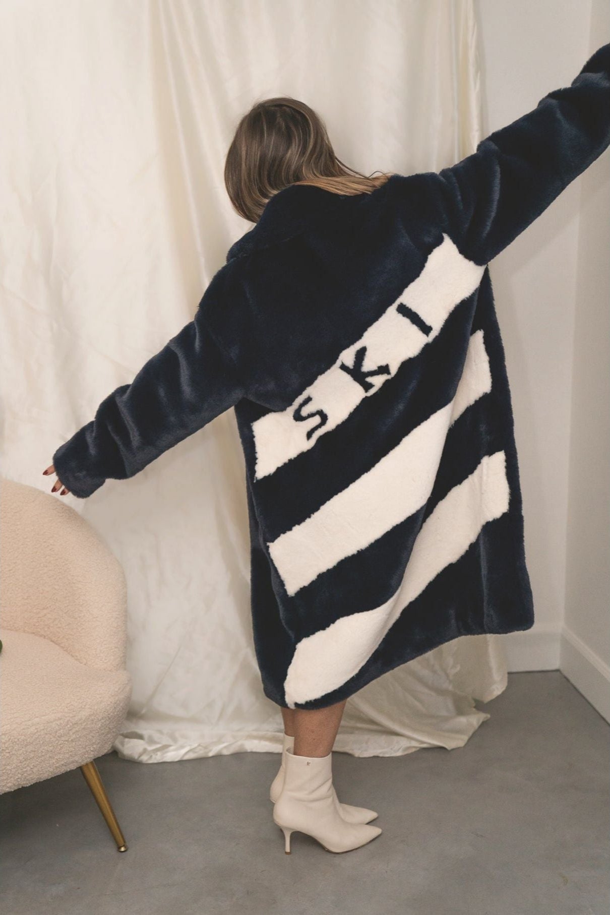 Back view of navy faux fur jacket with bold white diagonal stripes and “SKI” lettering — from the Mr. Greys collection.