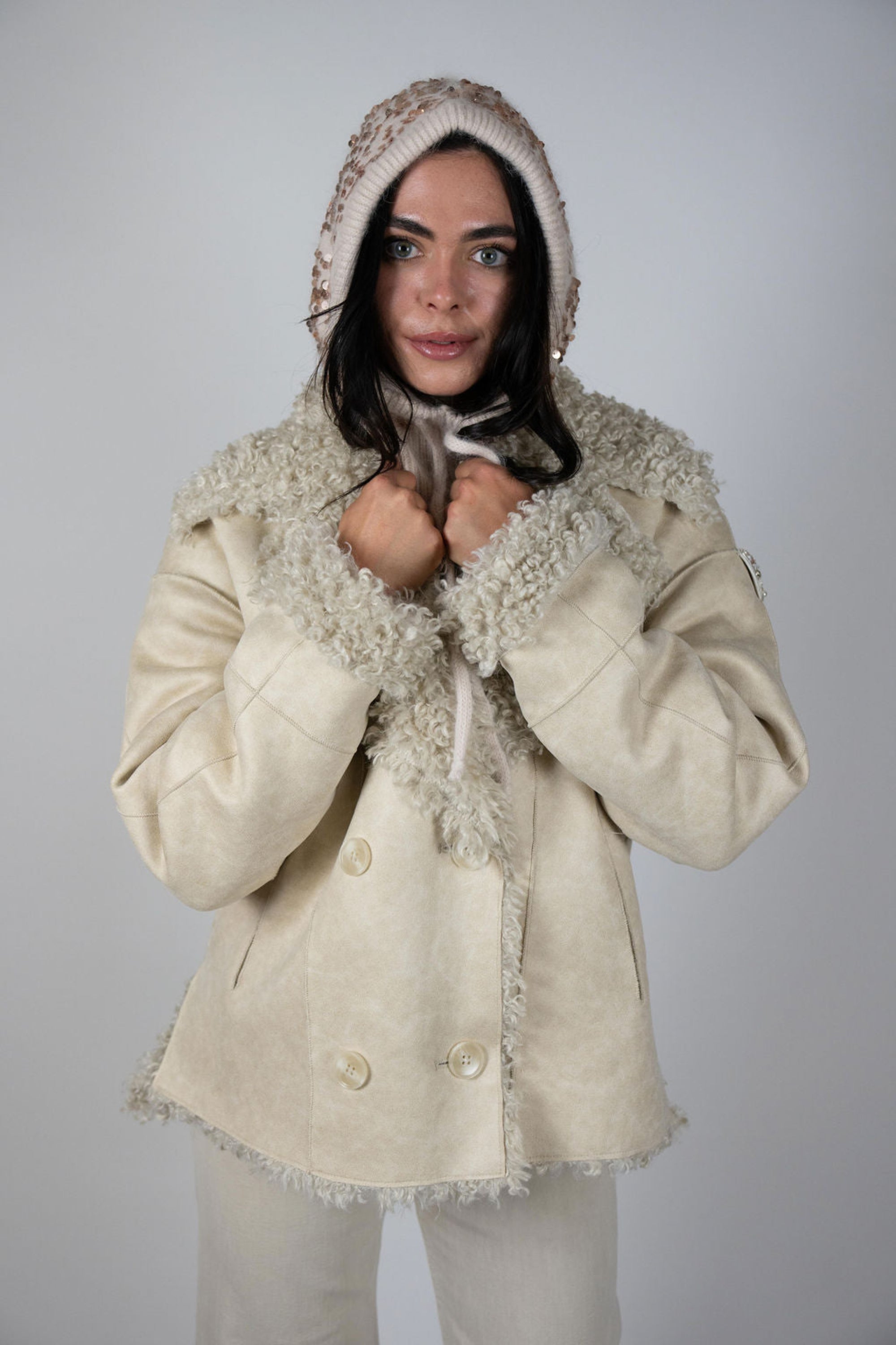 Woman wearing the cream Two Arrows Shearling Jacket with hood up, facing forward.