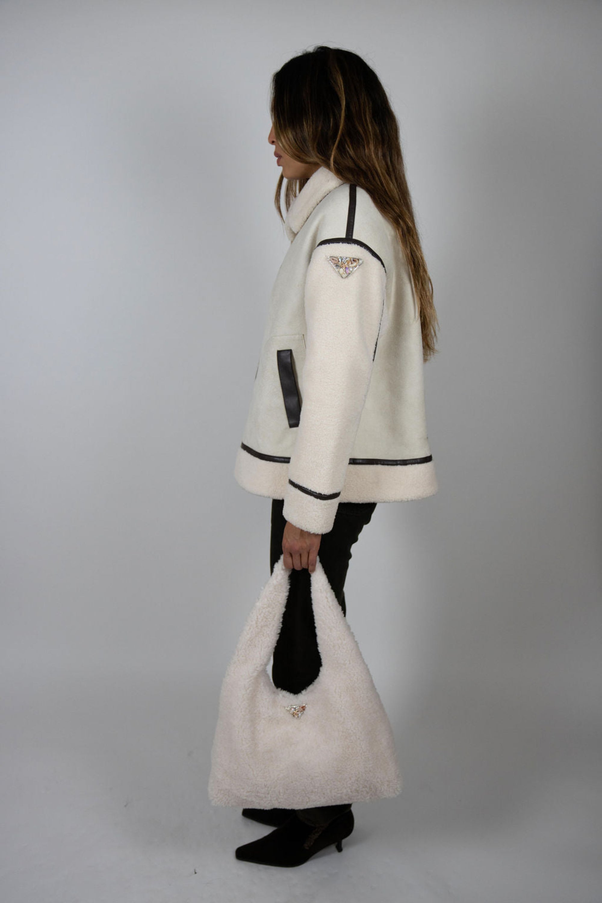 Full-length side view of model styling Angel Wings by Lucy Vandetta Jacket with sleek black pants