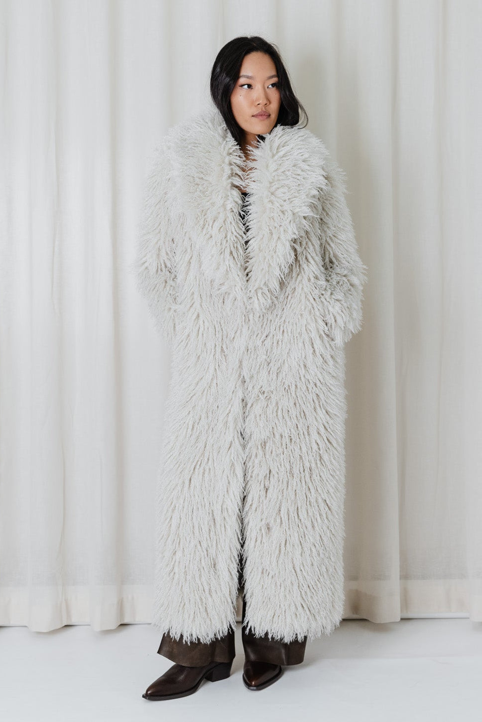 Front view of model wearing the Angel Wings Yeti Coat in Snow, a long shaggy faux-fur winter coat.