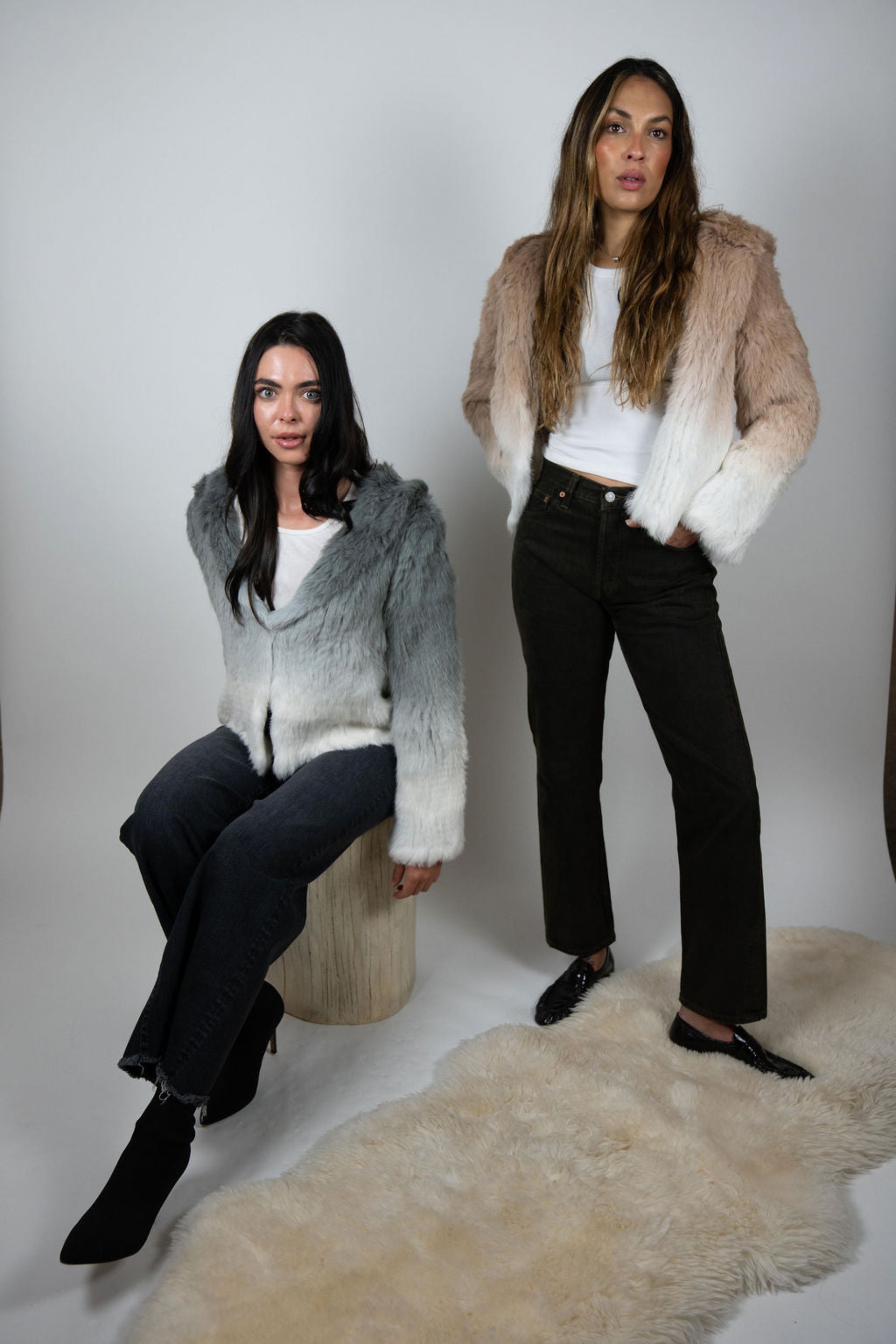 Two models wearing rabbit fur cropped jackets in beige and grey ombre with hoods