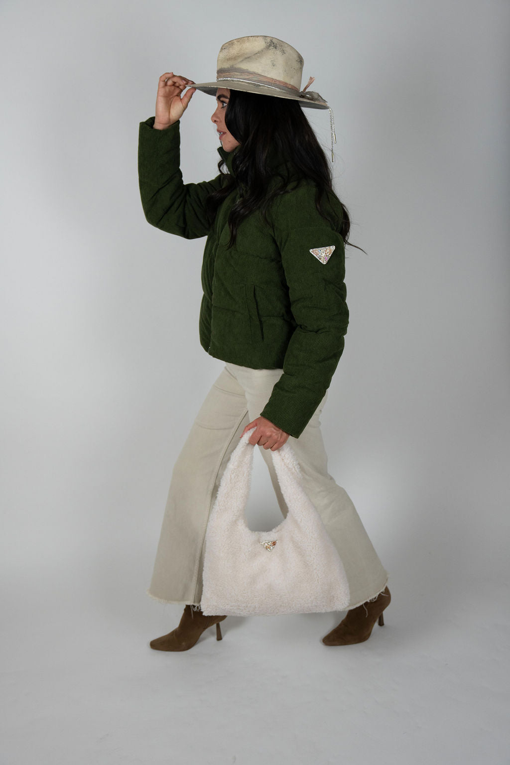 Model walking in olive Sundeck Jacket carrying cream fuzzy tote