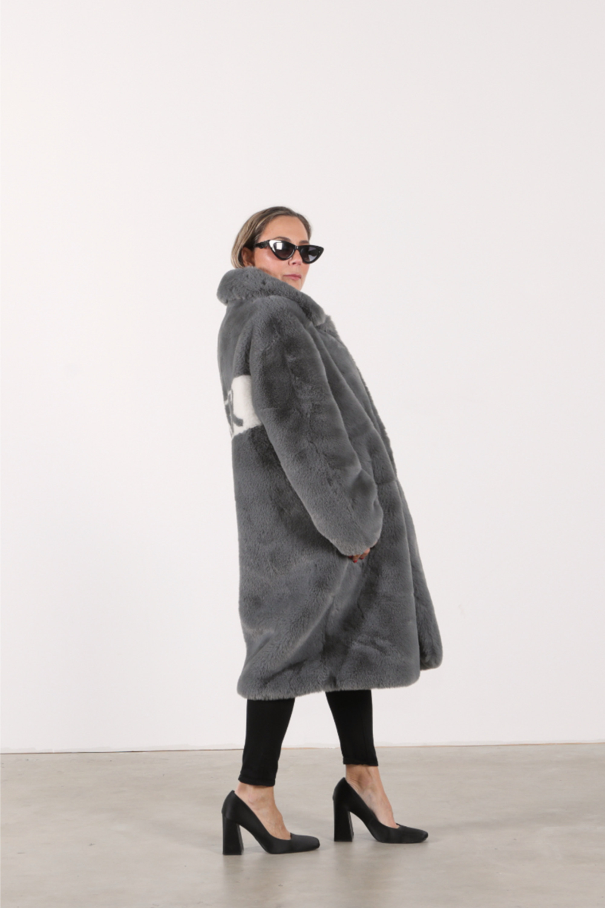 Back view of slate grey faux fur jacket with bold white diagonal panel featuring “FUCK” slogan in graphic lettering — part of the Mr. Greys collection.