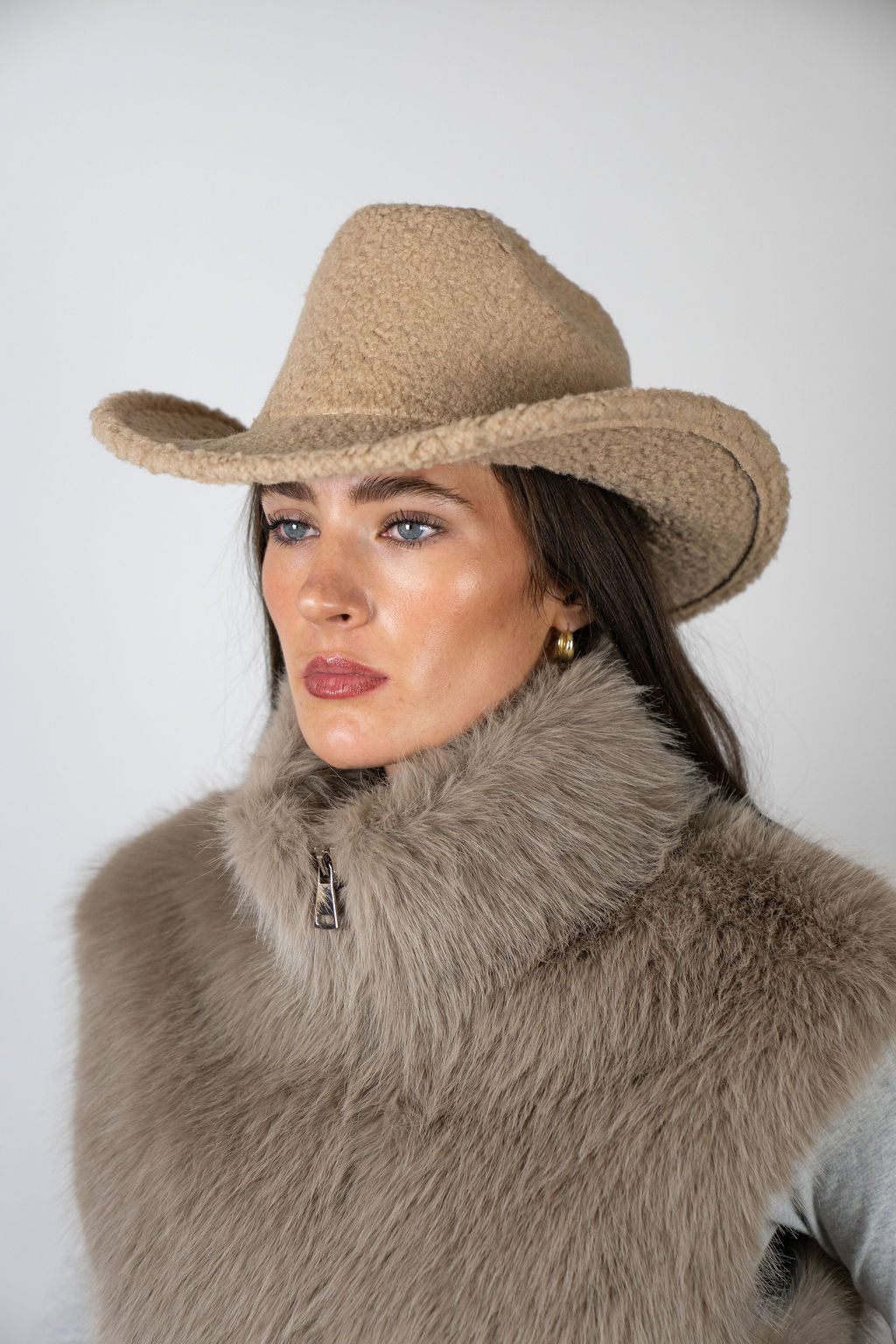 Model wearing the Cowboy Hat in Beige by Angel Wings by Lucy, styled with a faux fur vest for elevated western-inspired winter dressing.