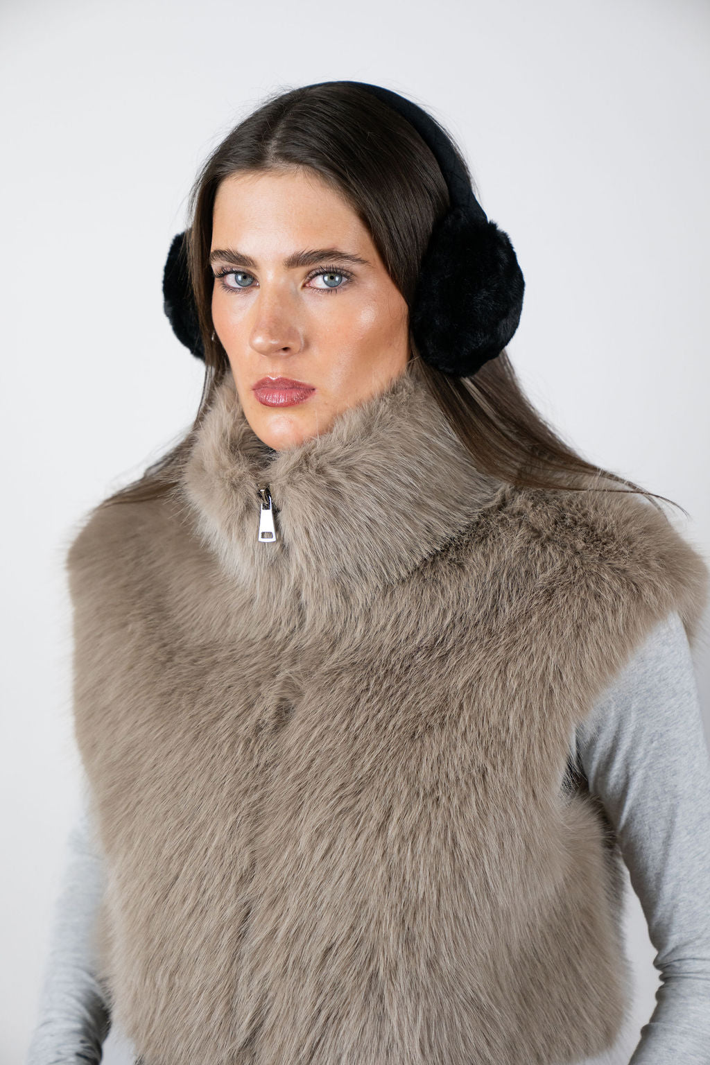 Model wearing faux fur earmuffs in Black by Angel Wings by Lucy, styled with a faux fur vest for elevated winter accessorising.