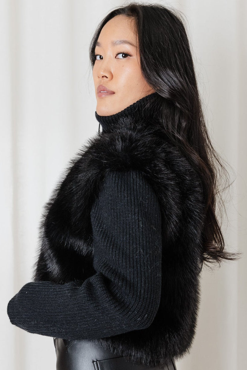 Angel Wings Snow Angel Knit in Black styled with leather pants, showing the textured faux-fur front and knit sleeves.