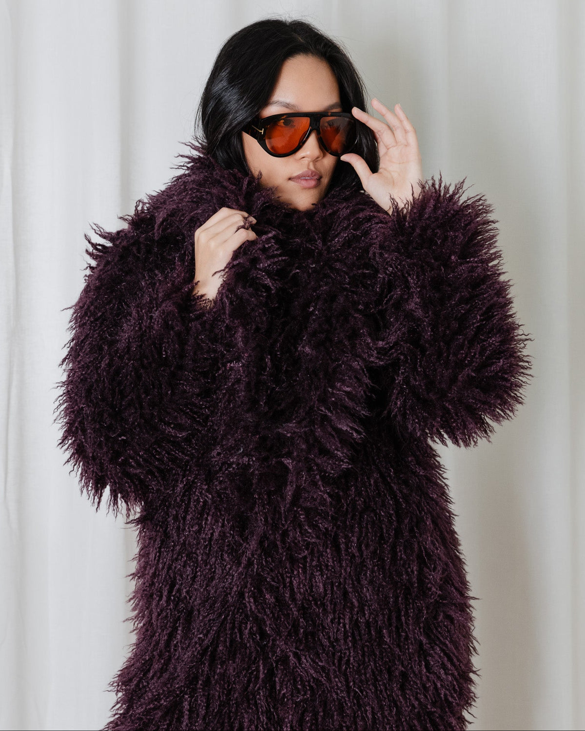 Model wearing the Angel Wings Yeti Coat in Bordeaux, featuring oversized shaggy faux fur and statement collar.