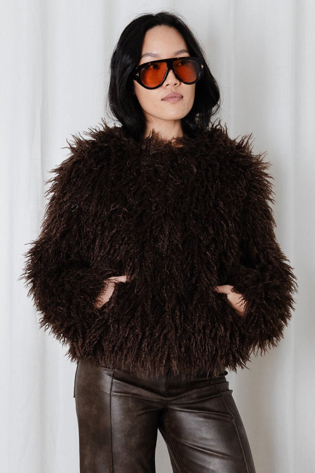 Model wearing the Angel Wings Yeti Jacket in Chocolate shaggy faux fur with brown leather pants.