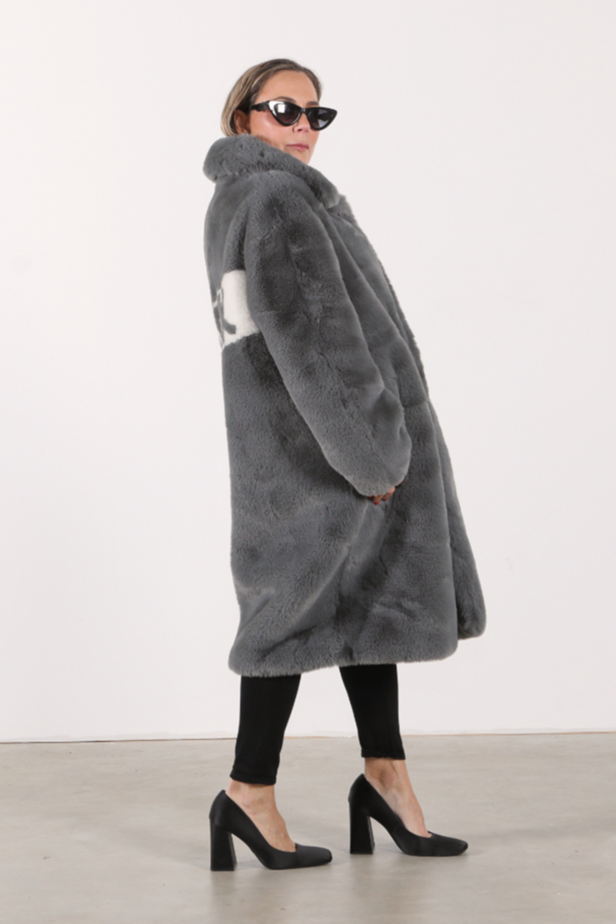 
Back view of slate grey faux fur jacket with bold white diagonal panel featuring “FUCK” slogan in graphic lettering — part of the Mr. Greys collection.